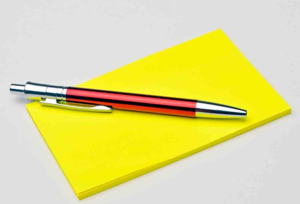 yellow post-it note pad with pen laying on top