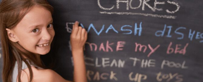 Child writing her chore list on chalkboard