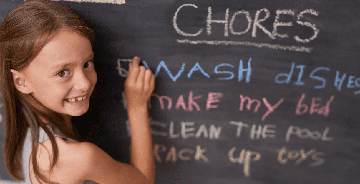 Child writing her chore list on chalkboard