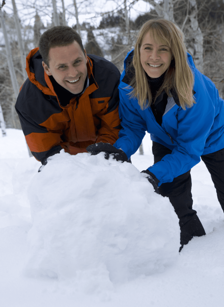 man and woman pushing a large snowball together