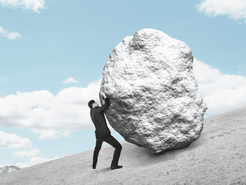 Man pushing a boulder up a hill