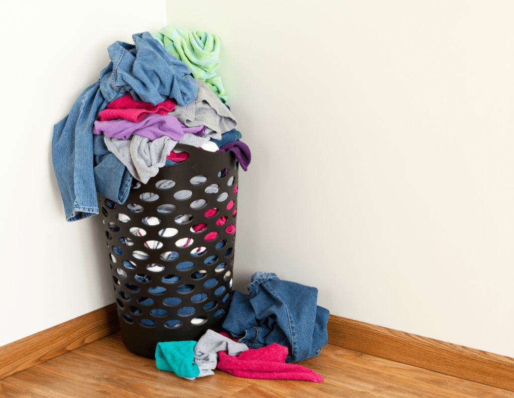 laundry hamper piled with clothes and clothes on the floor