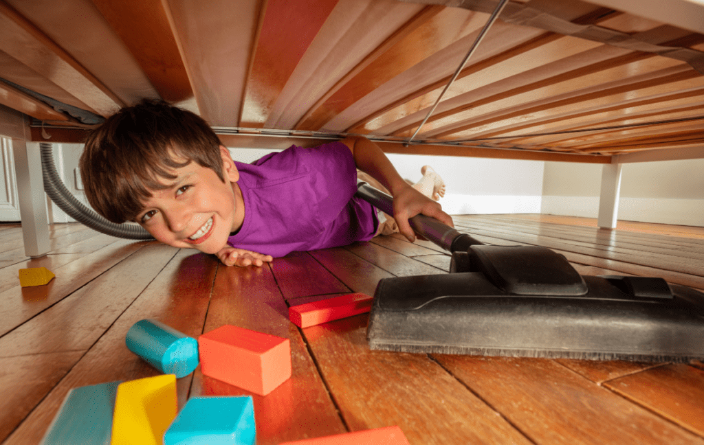 Little boy sweeping blocks out from under his bed