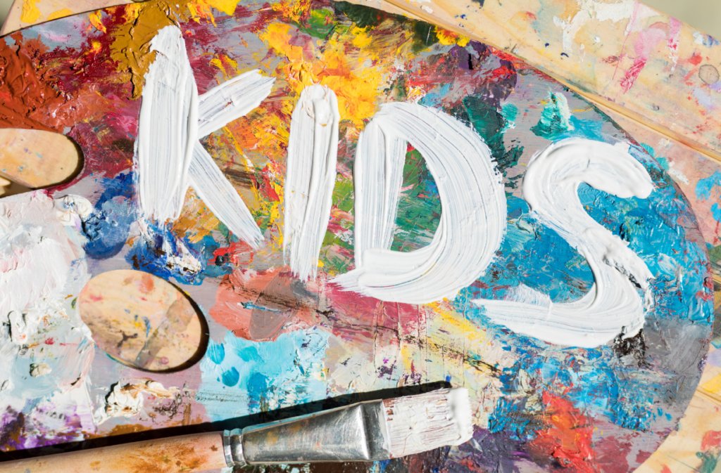 Artists palette with paint smeared on it and the word kids written on top