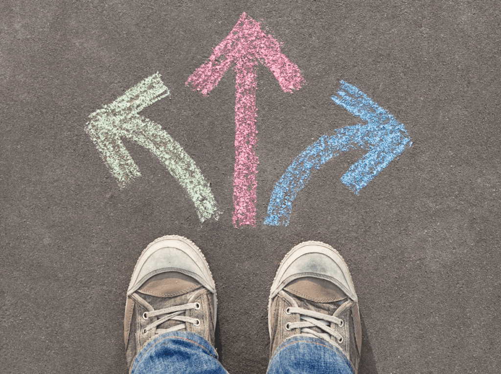 Feet on a sidewalk with 3 arrows drawn in sidewalk chalk that point left, right, and straight ahead.