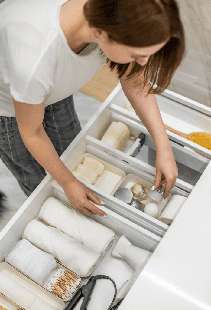 Woman straightening drawer in well-laid out bathroom vanity