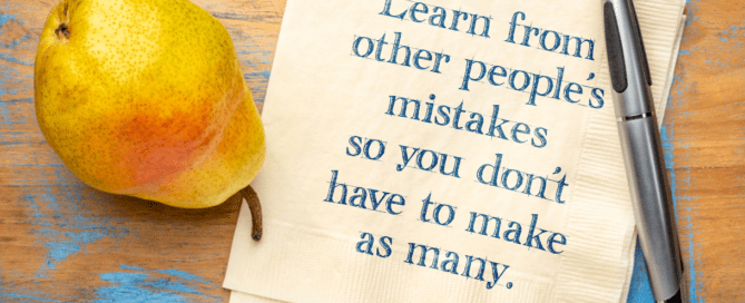 A pear is sitting on a table next to a note that says 'Learn from other people's mistakes so you don't have to make as many.'