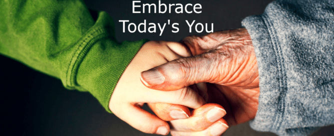 A young woman's hand grasps an old woman's hand against a dark background