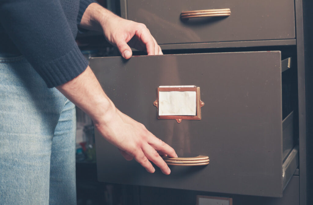 A woman's hands opening a file cabinet drawer
