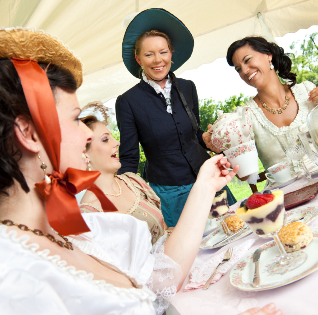 A group of 4 modern women in Victorian clothes enjoying tea at a party