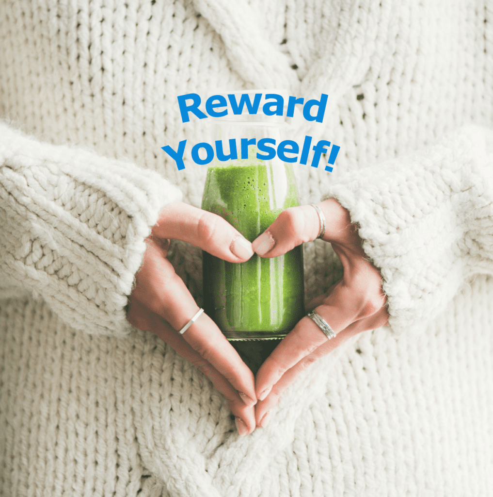 Woman in white sweater holding a green smoothie over her stomach and arranging hands in shape of a heart. Tagline says "Reward Yourself!"