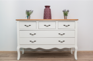 Simple, clutter-free white dresser with 3 simple vases on it.
