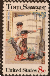 8 cent postage stamp of Tom Sawyer painting a white picket fence while a little boy watches.