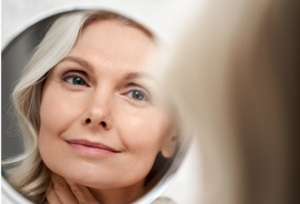 Mature woman looking in mirror and seeing her reflection